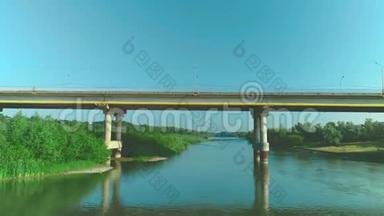 一辆汽车在宁静的河流上沿着桥路快速行驶的鸟瞰图。 4K.